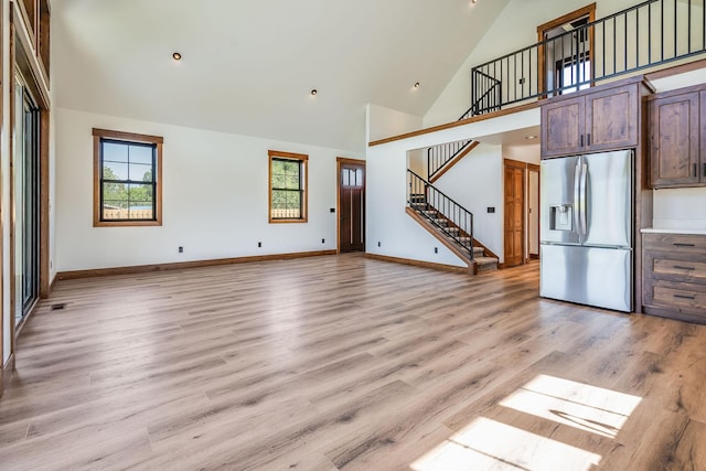 309 Stanton St, Plains, MT 59859 - unfurnished living room featuring high vaulted ceiling, stairway, light wood-style floors, and recessed lighting
