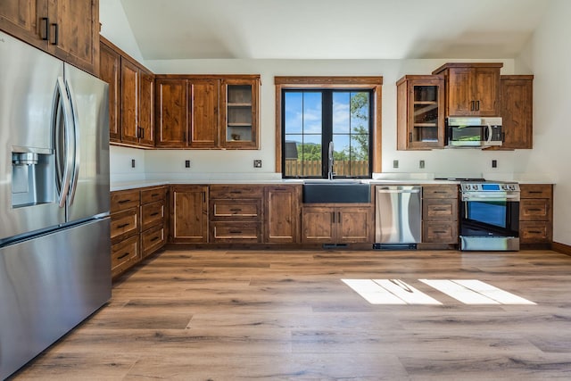 309 Stanton St, Plains, MT 59859 - kitchen featuring stainless steel appliances, light countertops, light wood-style floors, vaulted ceiling, and glass insert cabinets