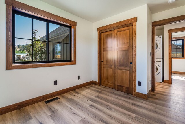 309 Stanton St, Plains, MT 59859 - unfurnished bedroom featuring stacked washer / drying machine, wood finished floors, and a closet