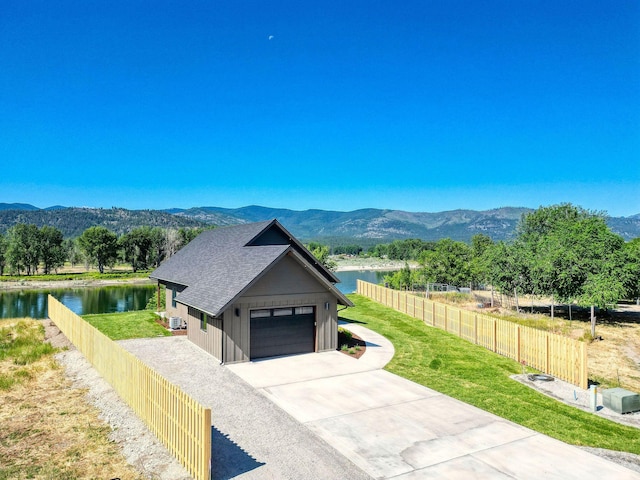 309 Stanton St, Plains, MT 59859 - view of front of house featuring a shingled roof, a garage, a water and mountain view, and driveway