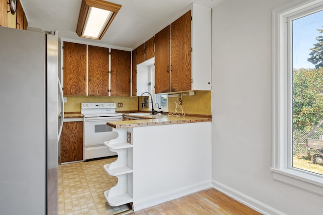 2515 S Higgins Ave, Missoula, MT 59801 - kitchen with freestanding refrigerator, white electric range, open shelves, brown cabinetry, and a peninsula