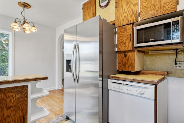 2515 S Higgins Ave, Missoula, MT 59801 - kitchen featuring appliances with stainless steel finishes, a chandelier, hanging light fixtures, light wood-type flooring, and arched walkways