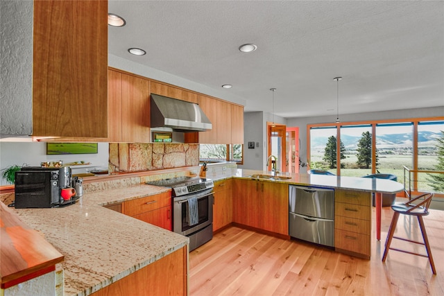 1087 Sunny Vista Rd, Helena, MT 59602 - kitchen with wall chimney range hood, stainless steel appliances, a peninsula, light stone counters, and recessed lighting