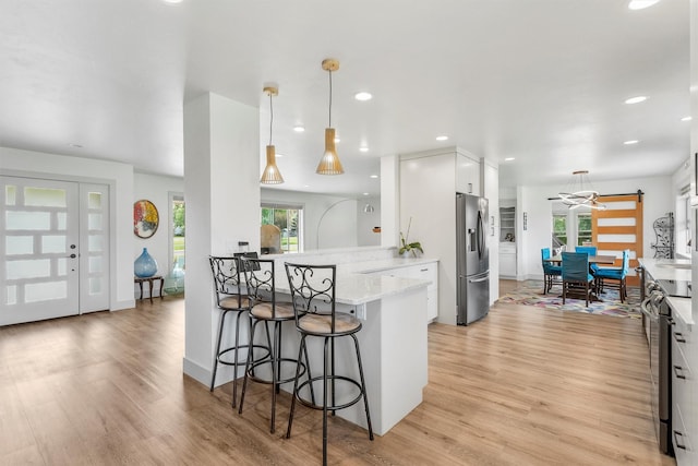 2709 Humble Rd, Missoula, MT 59804 - kitchen with stainless steel refrigerator with ice dispenser, white cabinetry, a kitchen breakfast bar, a peninsula, and light wood finished floors