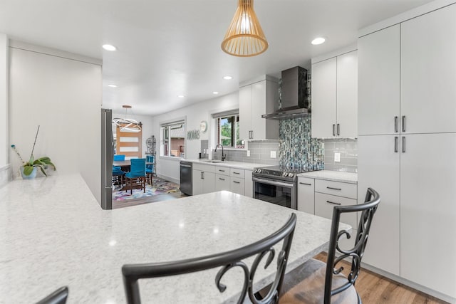 2709 Humble Rd, Missoula, MT 59804 - kitchen featuring wall chimney exhaust hood, stainless steel appliances, backsplash, white cabinetry, and recessed lighting