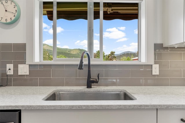 2709 Humble Rd, Missoula, MT 59804 - kitchen view of white cabinetry, tasteful backsplash, and light stone counters