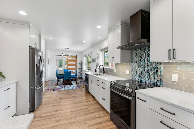 2709 Humble Rd, Missoula, MT 59804 - kitchen with appliances with stainless steel finishes, wall chimney range hood, light wood-style flooring, white cabinetry, and recessed lighting