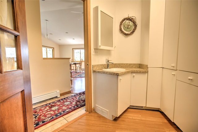 8319 Canyon Ferry Rd, Helena, MT 59602 - kitchen with baseboard heating, light wood-style floors, light countertops, white cabinetry, and lofted ceiling