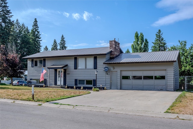 440 Dome Mountain Rd, Libby, MT 59923 - bi-level home with a chimney, an attached garage, concrete driveway, and a metal roof