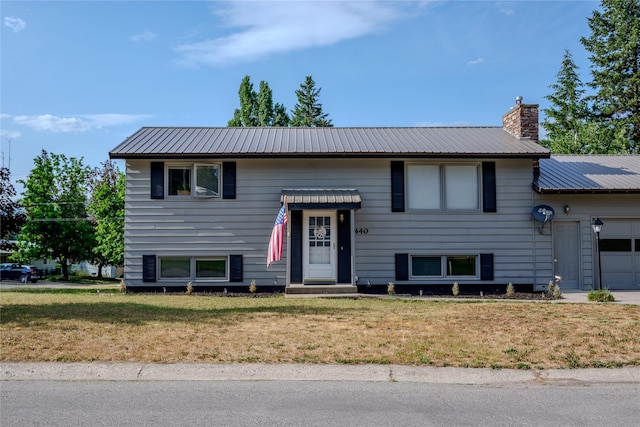 440 Dome Mountain Rd, Libby, MT 59923 - split foyer home with an attached garage, a front yard, a chimney, and a metal roof