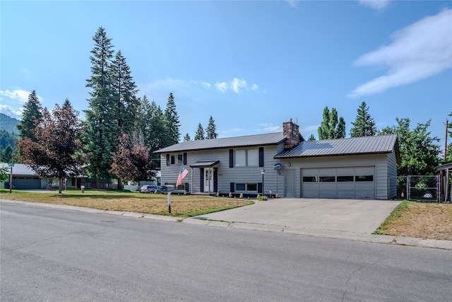 440 Dome Mountain Rd, Libby, MT 59923 - bi-level home featuring a chimney, concrete driveway, an attached garage, and a metal roof
