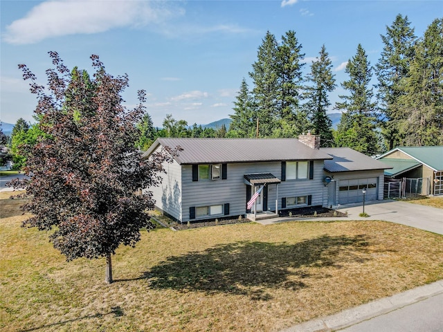 440 Dome Mountain Rd, Libby, MT 59923 - bi-level home featuring an attached garage, concrete driveway, a front lawn, and a chimney