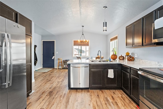 2009 22nd Ave S, Great Falls, MT 59405 - kitchen featuring stainless steel appliances, lofted ceiling, light wood-type flooring, a peninsula, and decorative light fixtures