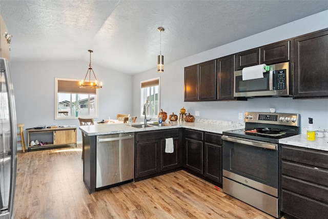 2009 22nd Ave S, Great Falls, MT 59405 - kitchen with stainless steel appliances, lofted ceiling, a peninsula, light wood-type flooring, and hanging light fixtures