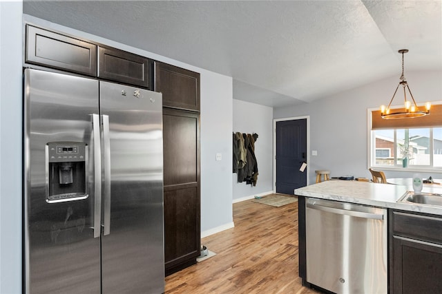 2009 22nd Ave S, Great Falls, MT 59405 - kitchen with stainless steel appliances, a chandelier, vaulted ceiling, dark brown cabinets, and light wood-type flooring