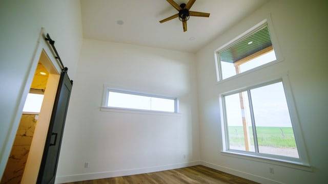 406 2nd Rd SW, Fairfield, MT 59436 - unfurnished room with healthy amount of natural light, a barn door, a ceiling fan, and wood finished floors
