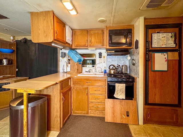 912 Muskrat Rd, Helmville, MT 59843 - kitchen with black appliances, light countertops, a peninsula, under cabinet range hood, and brown cabinetry
