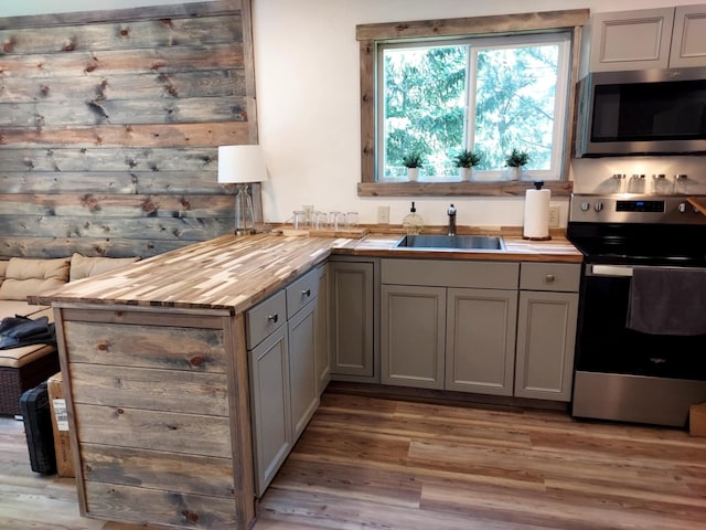 20536 Wild Horse Ranch Rd, Rollins, MT 59931 - kitchen featuring stainless steel appliances, gray cabinets, light wood-style flooring, a peninsula, and wood counters