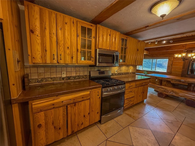 23254 Dayton Creek Rd, Proctor, MT 59929 - kitchen featuring stainless steel appliances, dark countertops, brown cabinetry, backsplash, and a textured ceiling