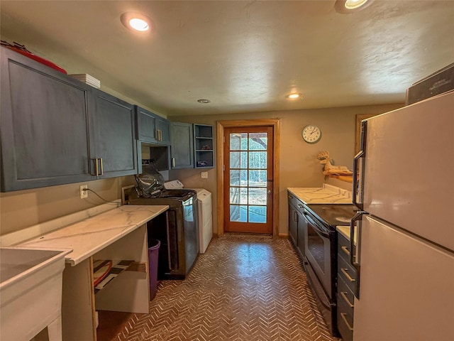 23254 Dayton Creek Rd, Proctor, MT 59929 - kitchen with freestanding refrigerator, tile patterned floors, stainless steel range with electric cooktop, light countertops, and washer and dryer