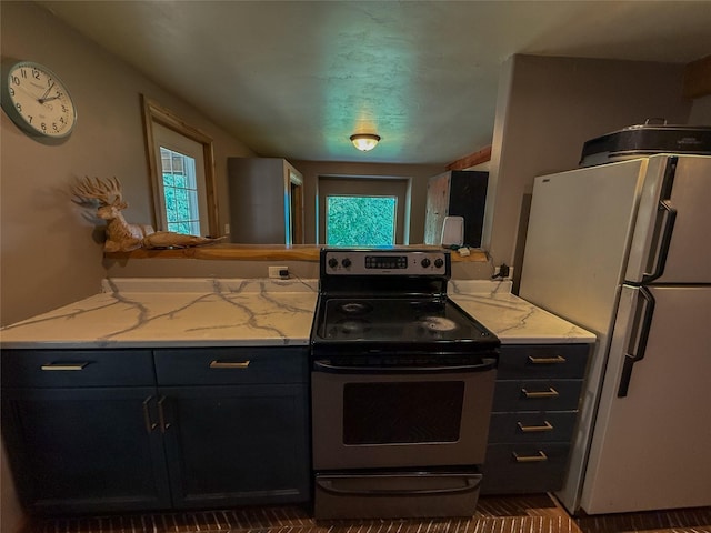 23254 Dayton Creek Rd, Proctor, MT 59929 - kitchen with stainless steel electric range, freestanding refrigerator, dark cabinetry, and light stone countertops
