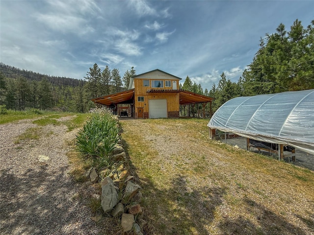 23254 Dayton Creek Rd, Proctor, MT 59929 - view of greenhouse with dirt driveway, a wooded view, and a garage