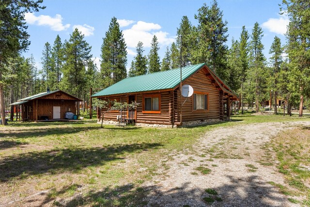 392 Leisure Ln, Sula, MT 59871 - view of home's exterior with log siding, a metal roof, and a yard