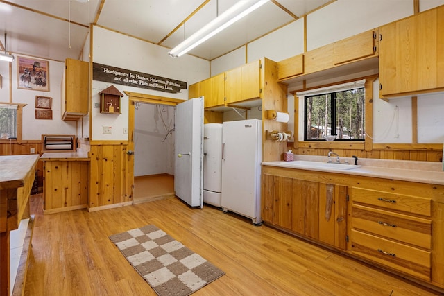 392 Leisure Ln, Sula, MT 59871 - kitchen featuring light wood-type flooring, freestanding refrigerator, a wainscoted wall, light countertops, and wooden walls