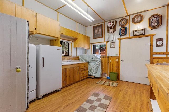 392 Leisure Ln, Sula, MT 59871 - kitchen with freestanding refrigerator, light wood-type flooring, wainscoting, and wooden walls