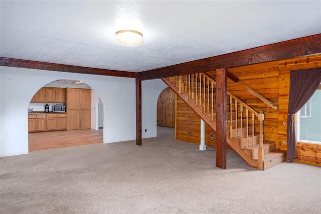 74 Cedar Crk, Libby, MT 59923 - unfurnished living room with light carpet, wooden walls, stairs, and arched walkways