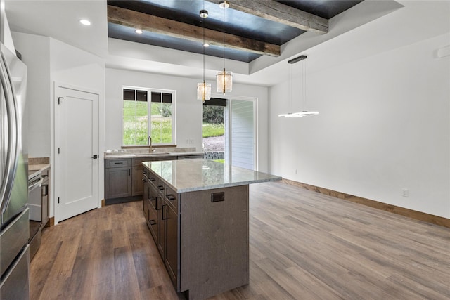 237 W Nicklaus Ave, Kalispell, MT 59901 - kitchen featuring dark wood-style floors, freestanding refrigerator, light stone counters, a kitchen island, and pendant lighting