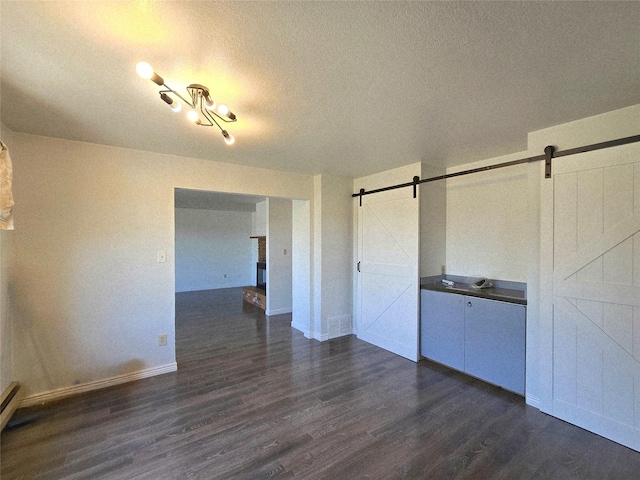 1401 Park Garden Rd, Great Falls, MT 59404 - unfurnished room with a barn door, dark wood-style floors, and a textured ceiling