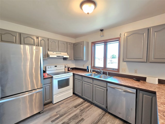 1401 Park Garden Rd, Great Falls, MT 59404 - kitchen with stainless steel appliances, gray cabinetry, under cabinet range hood, light wood finished floors, and dark countertops
