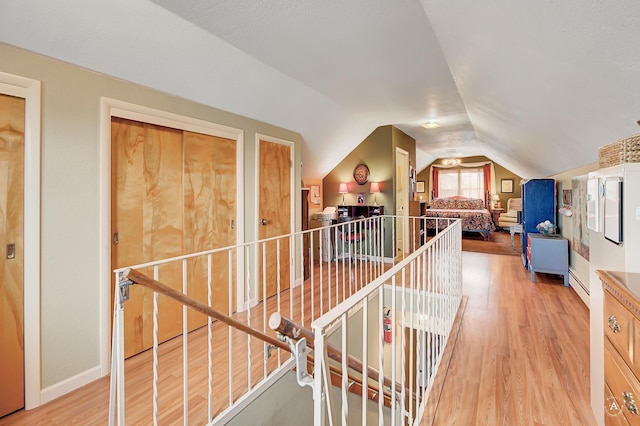 216 W Riggs St, East Helena, MT 59635 - hallway featuring an upstairs landing, vaulted ceiling, light wood-type flooring, and baseboard heating