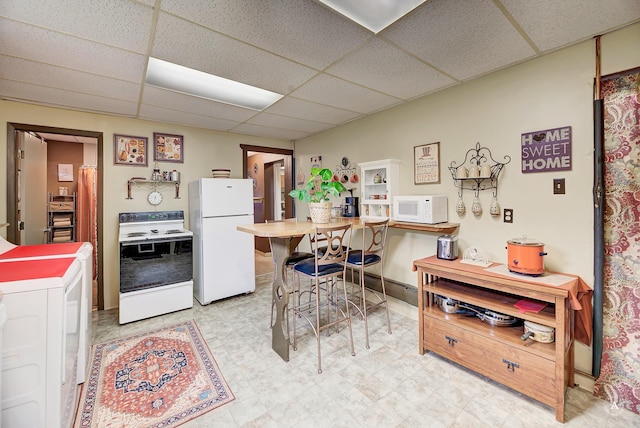 216 W Riggs St, East Helena, MT 59635 - kitchen featuring white appliances, a paneled ceiling, and light floors