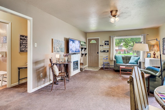 216 W Riggs St, East Helena, MT 59635 - living area featuring carpet flooring, a glass covered fireplace, a ceiling fan, a textured ceiling, and baseboard heating
