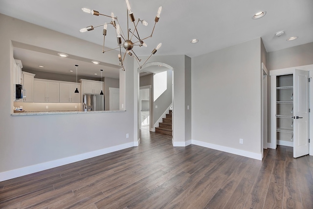 2933 Travis Ave, Helena, MT 59601 - unfurnished living room with arched walkways, dark wood-style floors, recessed lighting, a chandelier, and stairway