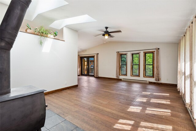 28578 Wapiti Ln, Bigfork, MT 59911 - unfurnished living room with a baseboard heating unit, a wood stove, a skylight, vaulted ceiling, and a ceiling fan