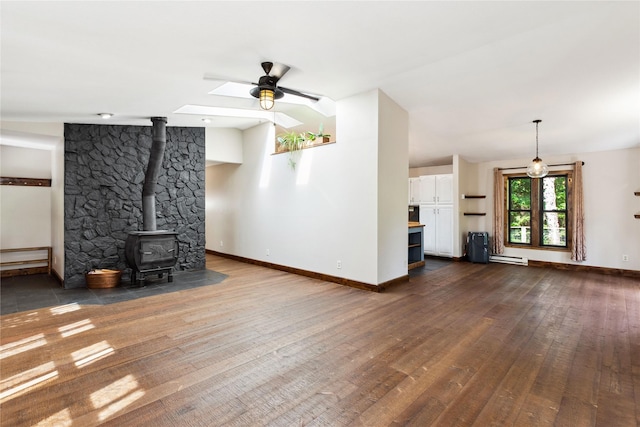 28578 Wapiti Ln, Bigfork, MT 59911 - unfurnished living room with a ceiling fan, a wood stove, dark wood-style floors, a baseboard radiator, and a skylight