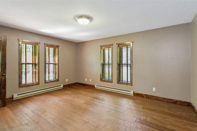 28578 Wapiti Ln, Bigfork, MT 59911 - empty room featuring a baseboard heating unit, wood finished floors, and plenty of natural light