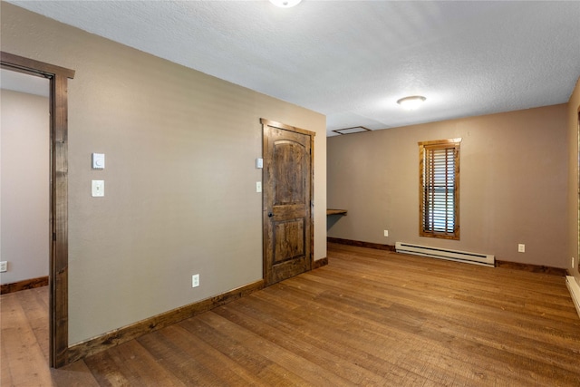 28578 Wapiti Ln, Bigfork, MT 59911 - unfurnished room featuring a baseboard radiator, wood finished floors, and a textured ceiling