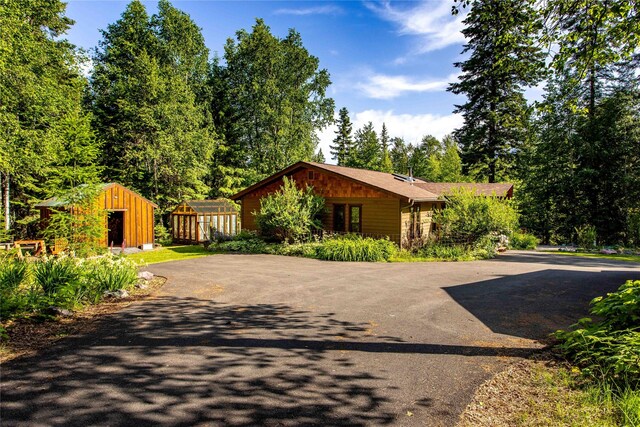 28578 Wapiti Ln, Bigfork, MT 59911 - view of front of home featuring asphalt driveway, a shed, and stone siding