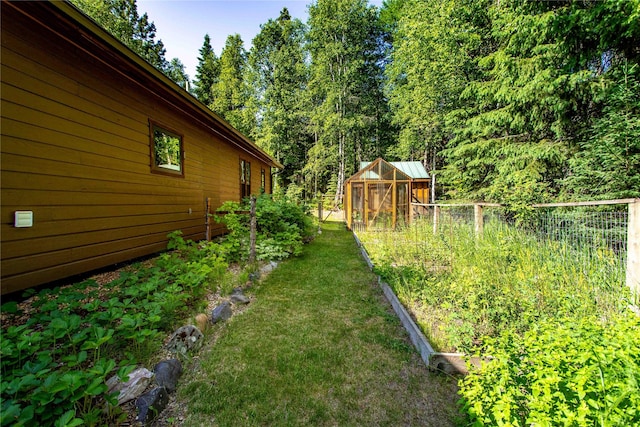 28578 Wapiti Ln, Bigfork, MT 59911 - view of yard featuring a greenhouse, a vegetable garden, and an outdoor structure