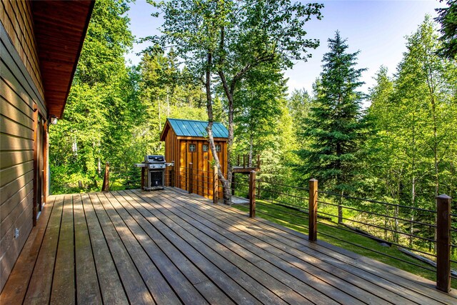 28578 Wapiti Ln, Bigfork, MT 59911 - wooden deck featuring a storage unit, a grill, and a view of trees