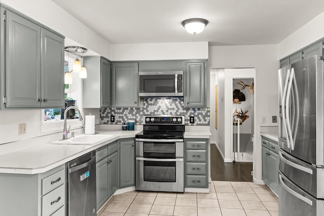3906 Bellecrest Dr, Missoula, MT 59801 - kitchen featuring appliances with stainless steel finishes, gray cabinets, light countertops, light tile patterned floors, and decorative backsplash