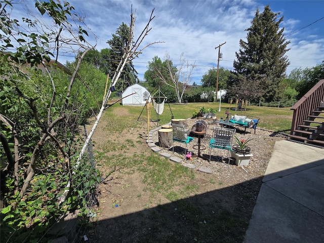 761 32nd Ave NE, Great Falls, MT 59404 - view of grassy yard with an outdoor fire pit, stairs, a storage unit, and a patio