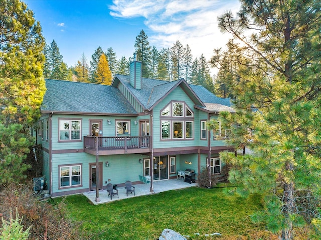 151 Whisper Ridge Dr, Bigfork, MT 59911 - back of property with a yard, a chimney, a patio area, a shingled roof, and a wooden deck