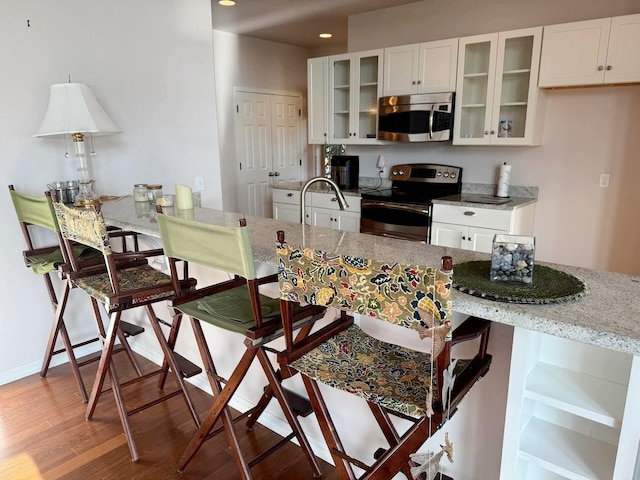 151 Whisper Ridge Dr, Bigfork, MT 59911 - kitchen with stainless steel appliances, light wood-style flooring, a kitchen breakfast bar, light stone countertops, and recessed lighting
