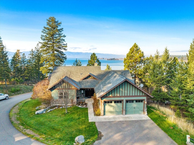 151 Whisper Ridge Dr, Bigfork, MT 59911 - view of front of home featuring driveway, an attached garage, a front yard, a chimney, and roof with shingles