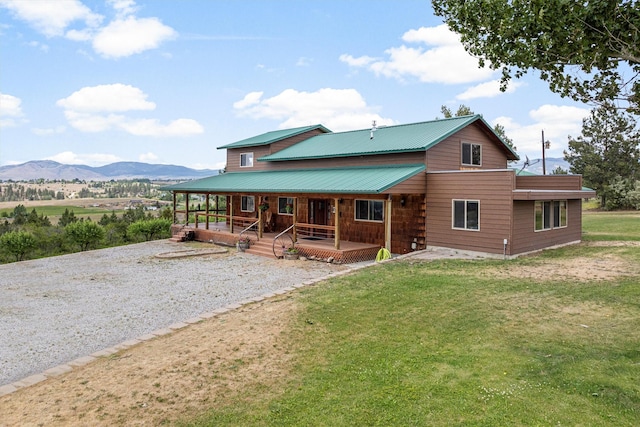 674 Porter Hill Rd, Stevensville, MT 59870 - back of house with a mountain view, covered porch, a yard, driveway, and a metal roof